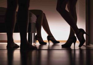 man and womens in heels legs by a bed